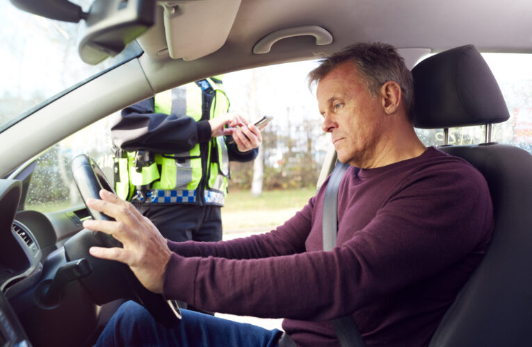 Male Driver Being Stopped By Female Traffic Police Officer With Digital Tablet For Driving Offence